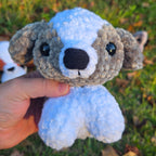 Hand holding a small crocheted animal toy against a grassy background
